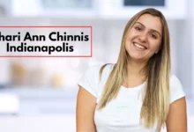 Shari Ann Chinnis from Indianapolis, smiling warmly with straight, light brown hair. She is wearing a white t-shirt and standing in a modern indoor space with a blurred background, possibly a kitchen. The atmosphere is casual and welcoming, with text overlaying the image that reads "Shari Ann Chinnis Indianapolis" in bold black font framed by a red border