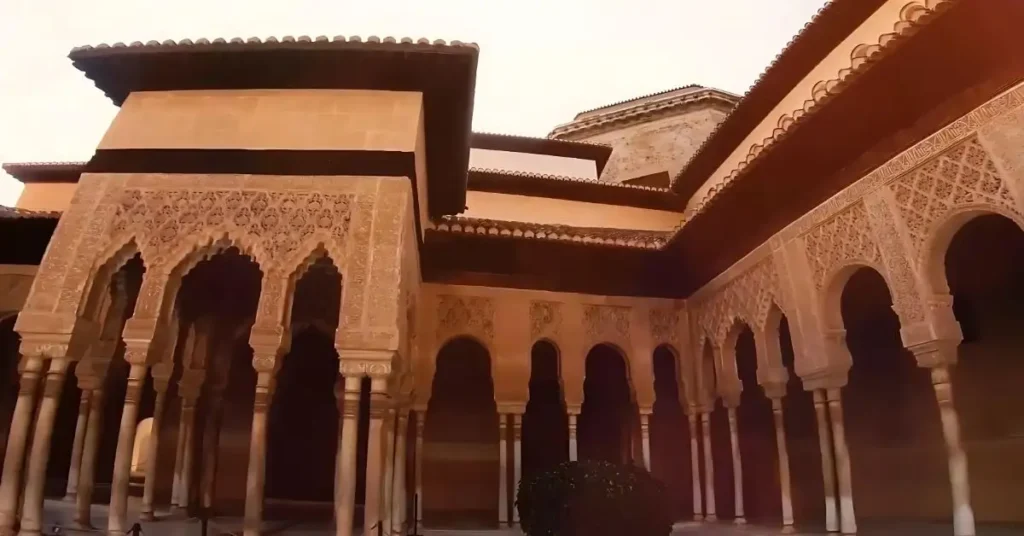 The serene courtyard of Alhambra Palace in Granada, Spain, showcasing intricate architecture and lush greenery.