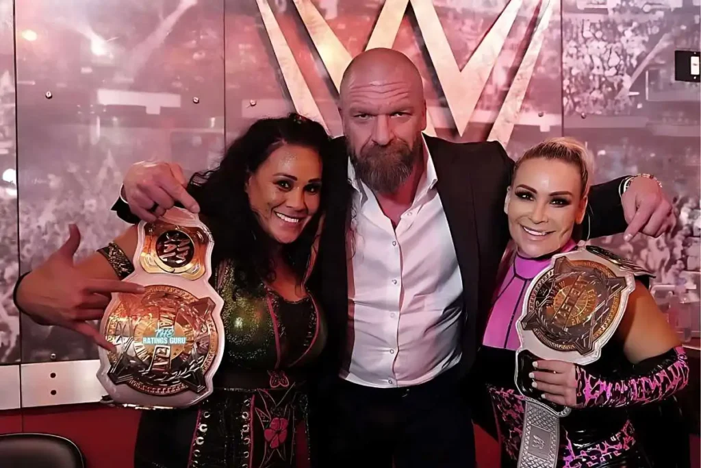 Two women and a man proudly display their WWE championship belts, celebrating their victory from WWE SmackDown Episode 1491.