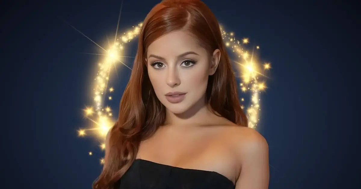 Portrait of Vanna Bardeau, a woman with long, reddish-brown hair, wearing an off-shoulder black outfit. She stands against a dark blue background illuminated by a glowing ring of golden sparkles, creating a glamorous and captivating aura.